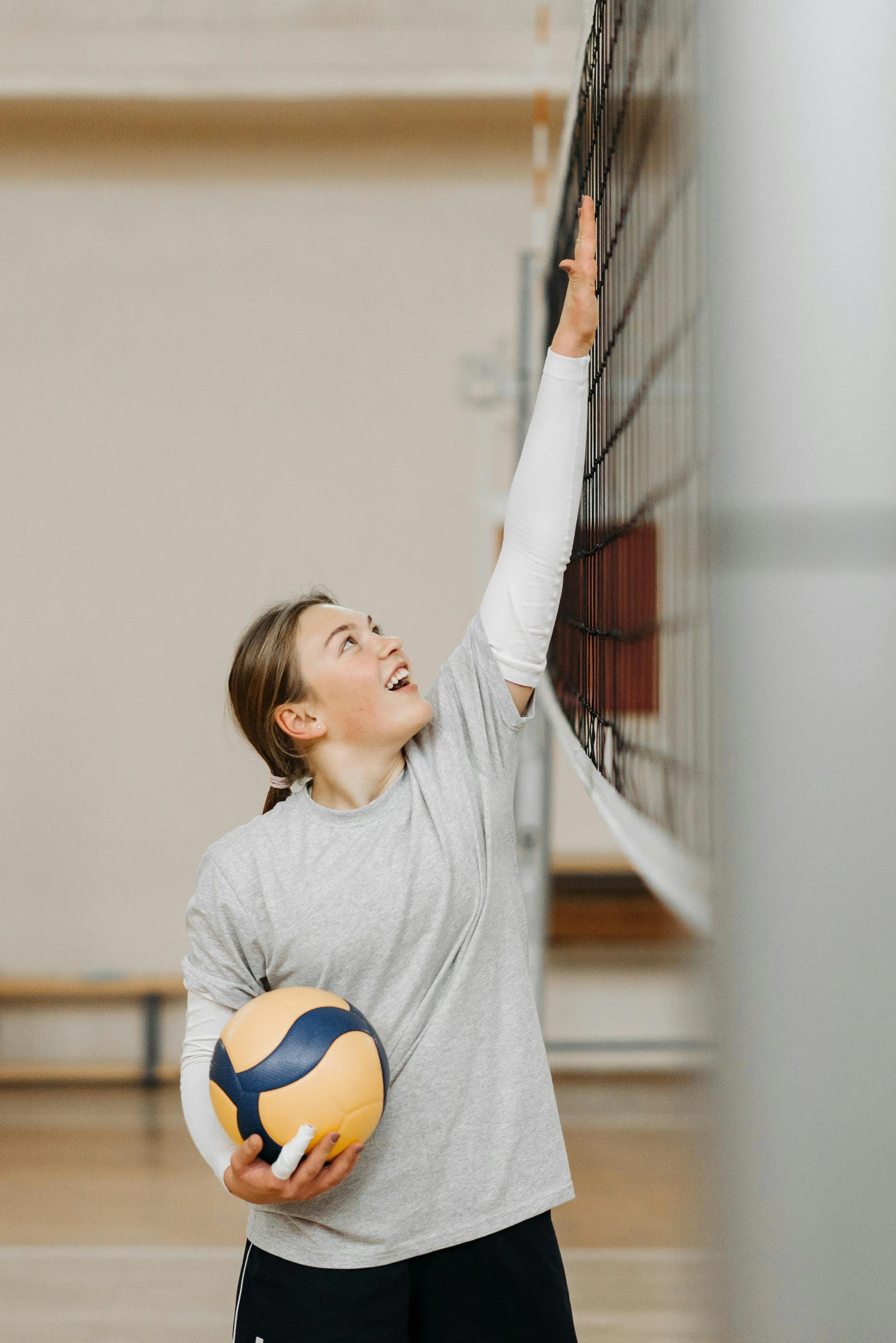 a lady holds the back of the net to keep her balance while playing volleyball