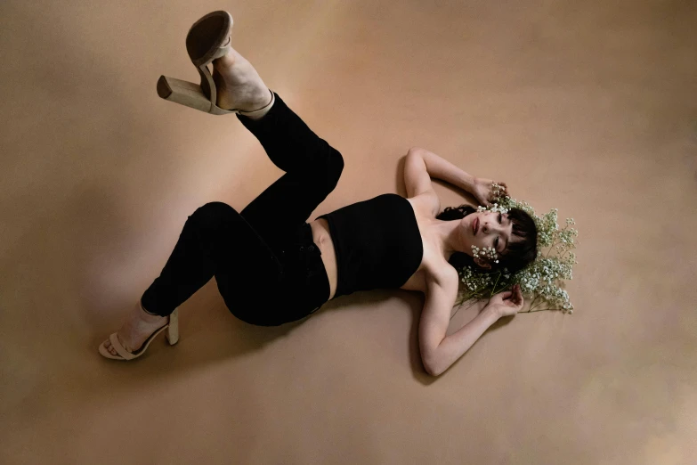 a woman in black shirt laying on floor with shoes