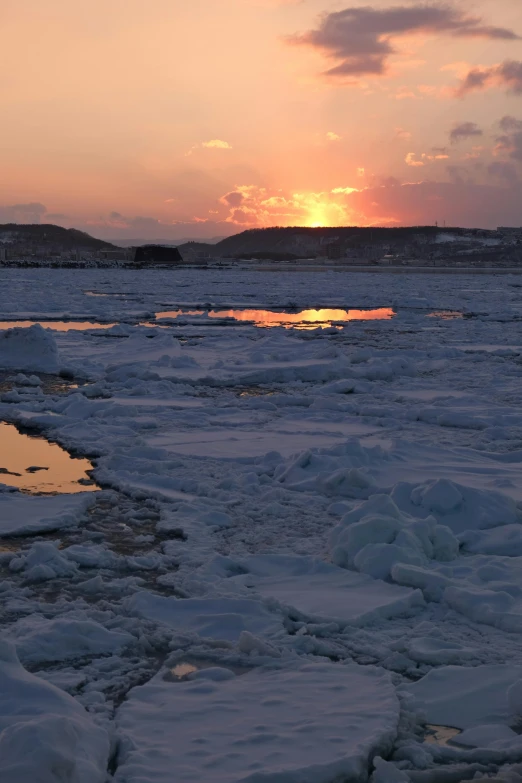 the sun is setting over some ice in a lake