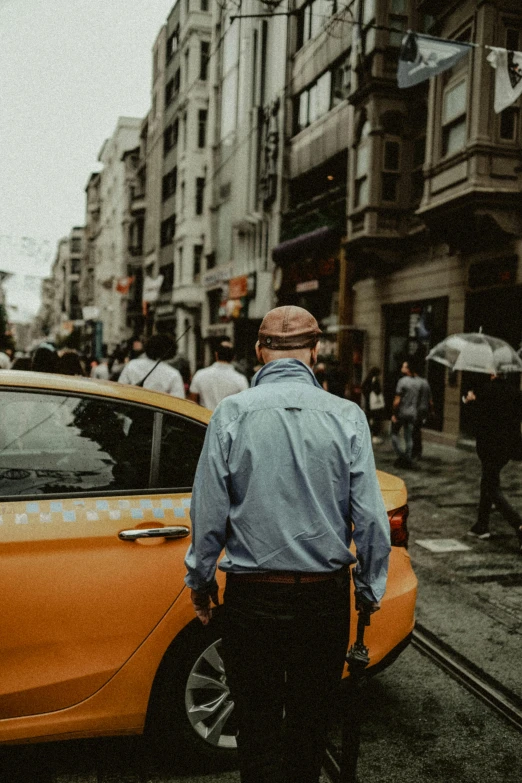 man in blue dress shirt standing near cars with umbrellas on the street