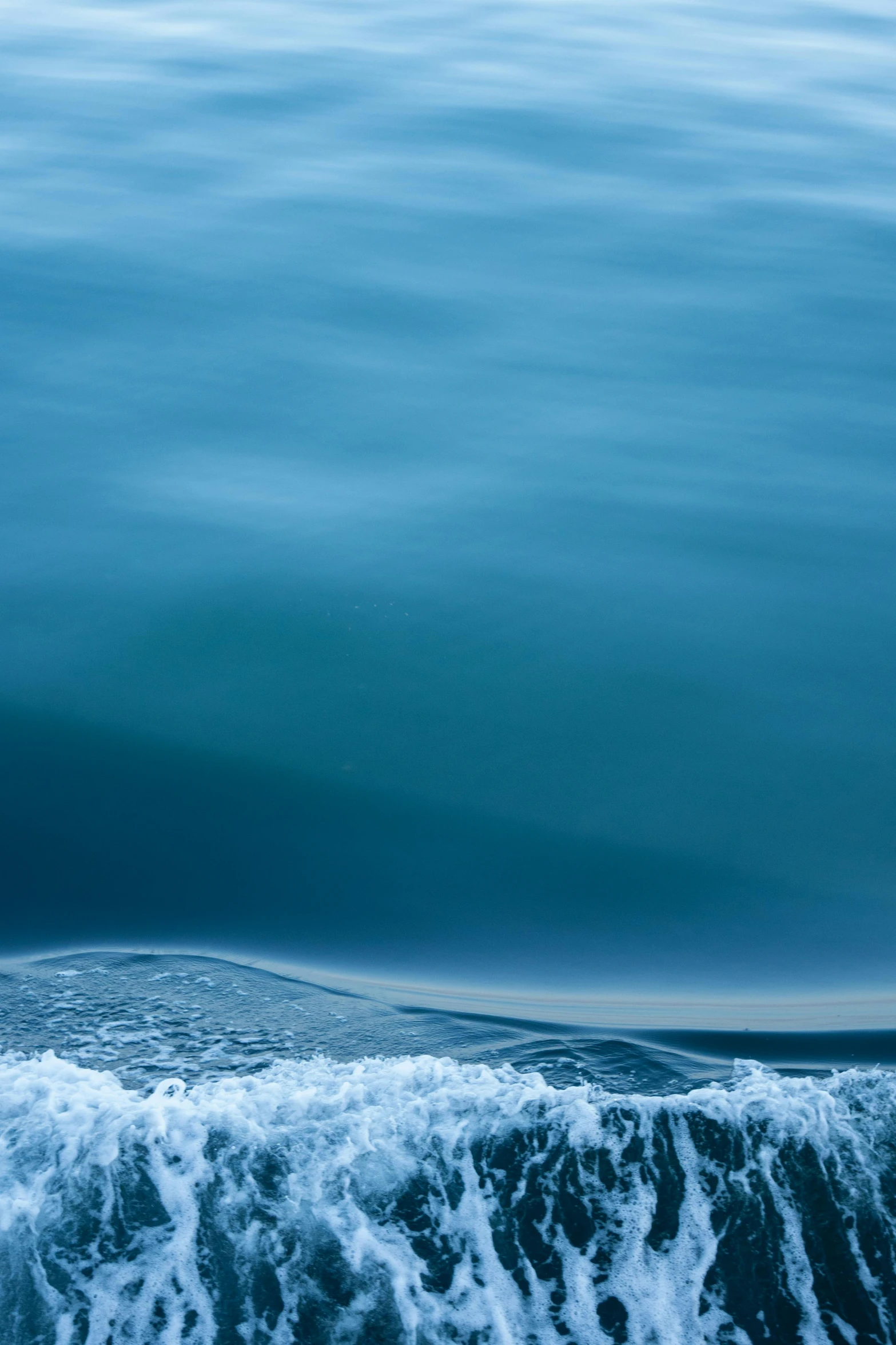 a view of the surface of a body of water from the side of a boat