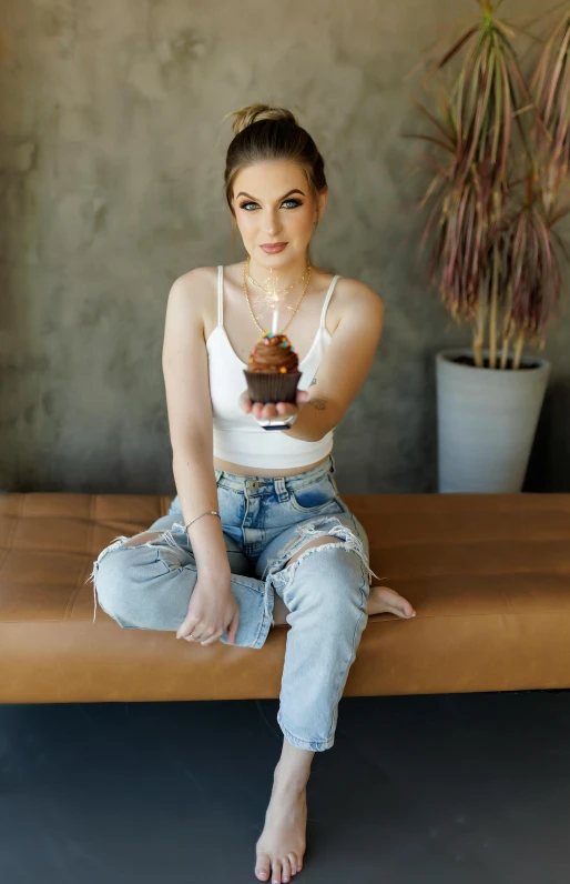 woman in a white tank top holding a piece of chocolate cake