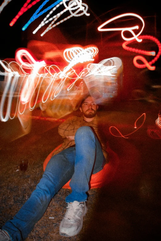 a man sitting on the ground in front of blurry lights