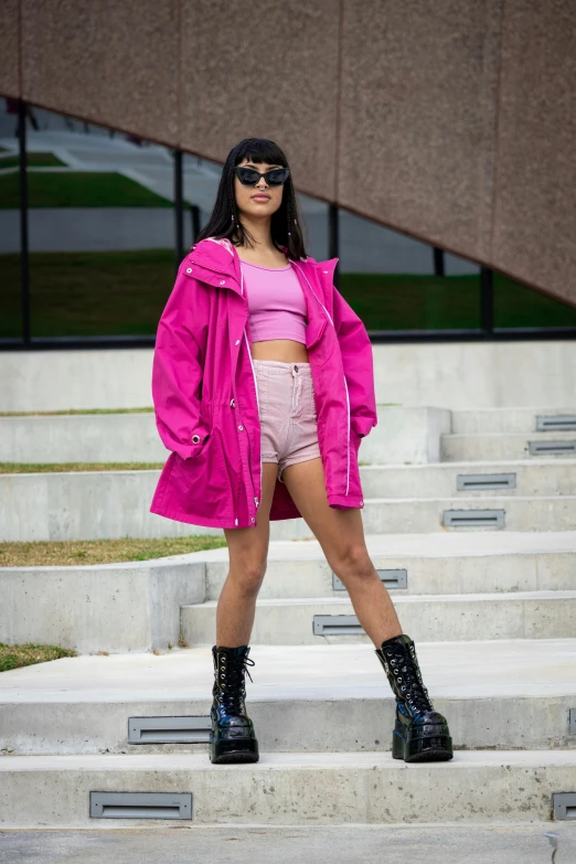 woman standing on steps with bright pink jacket and purple top