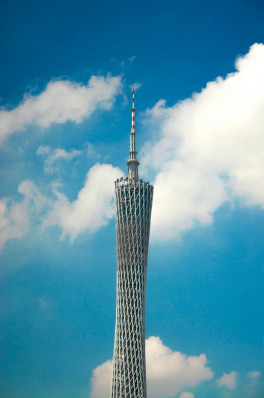 a tall tower is surrounded by clouds and blue skies