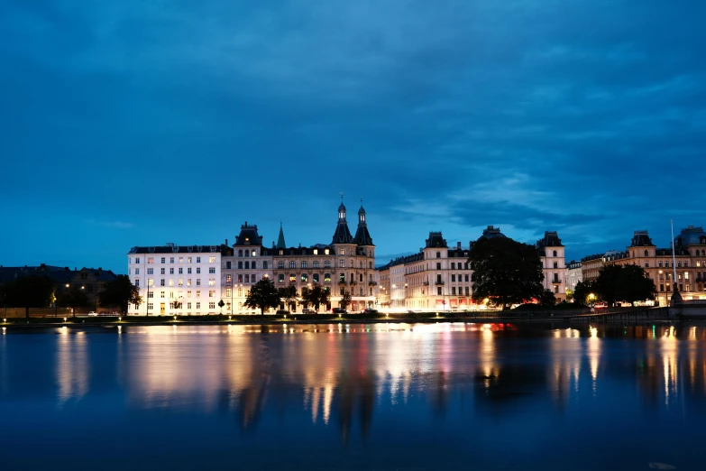 several large buildings lit up on the side of the water