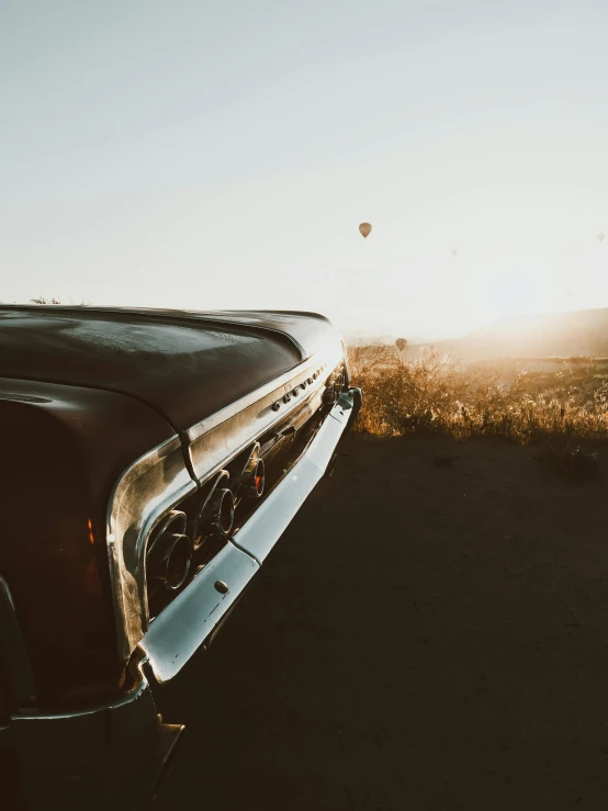 the front of a truck on a field with a balloon in the sky