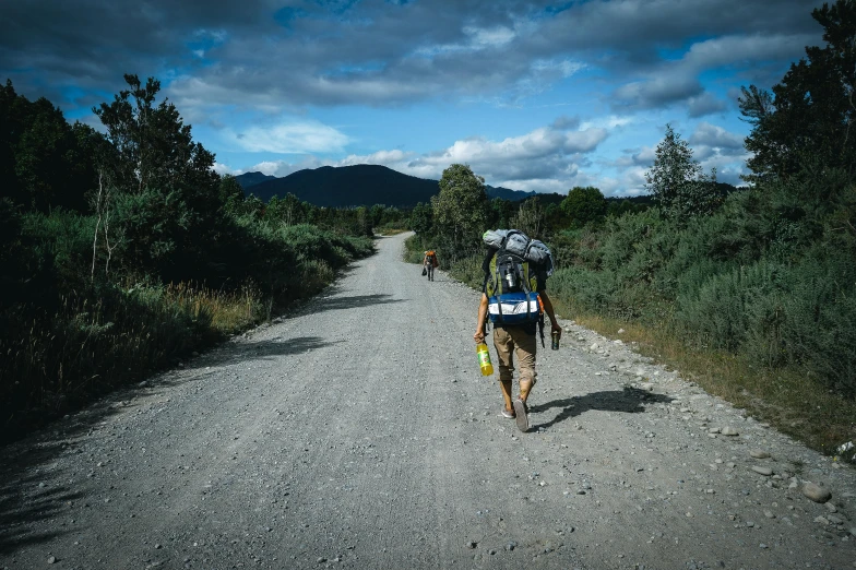 a person walking across a gravel road with trees on either side