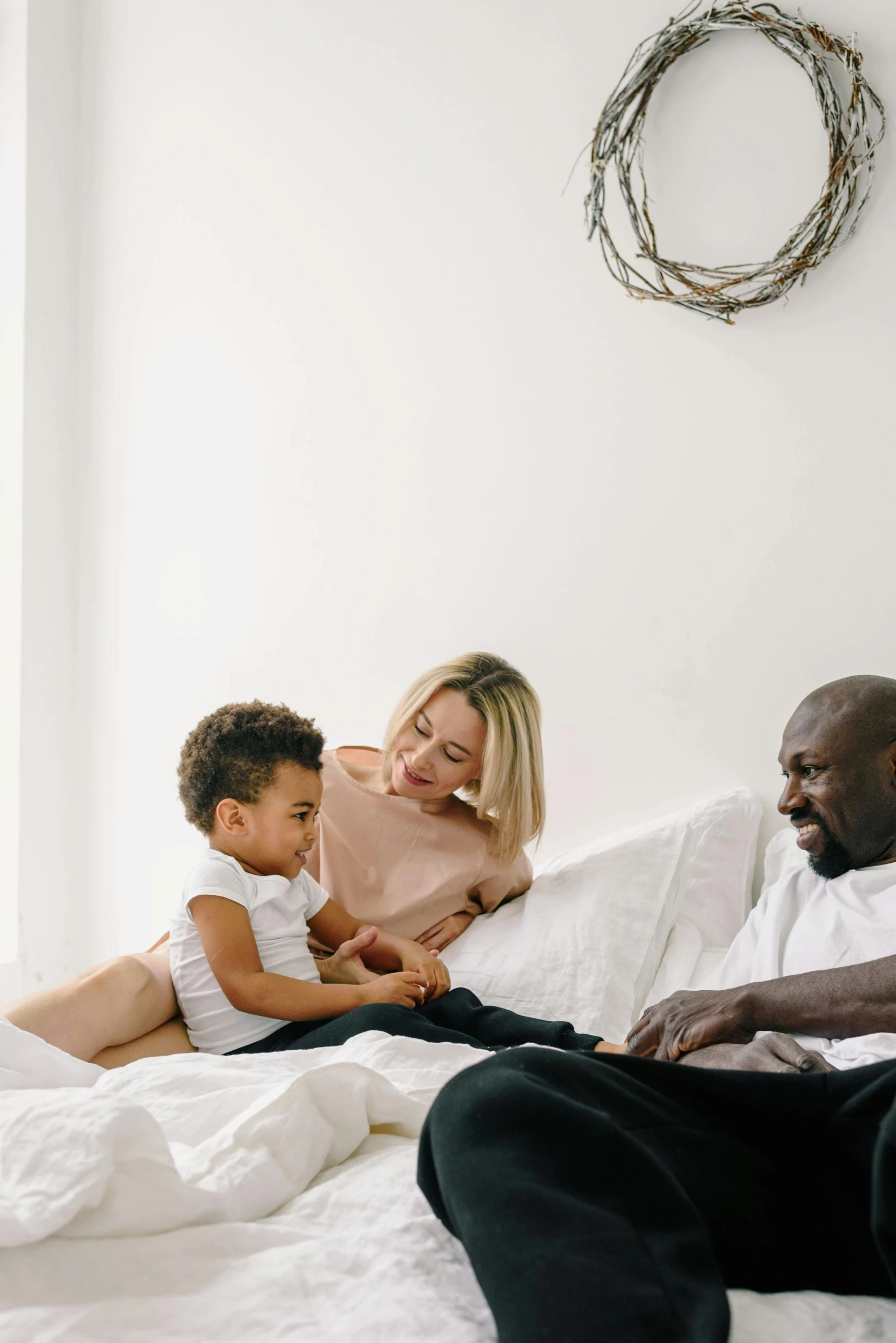 a woman, child, and adult lying on a bed