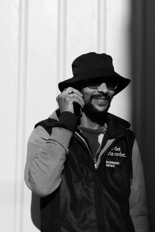 a bearded man holding a cell phone and looking at the camera