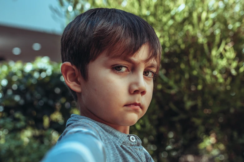 a small boy in a blue shirt is posing for the camera