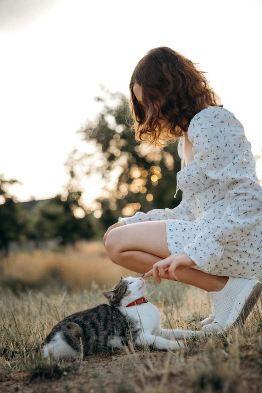 a woman sitting in the grass with a cat