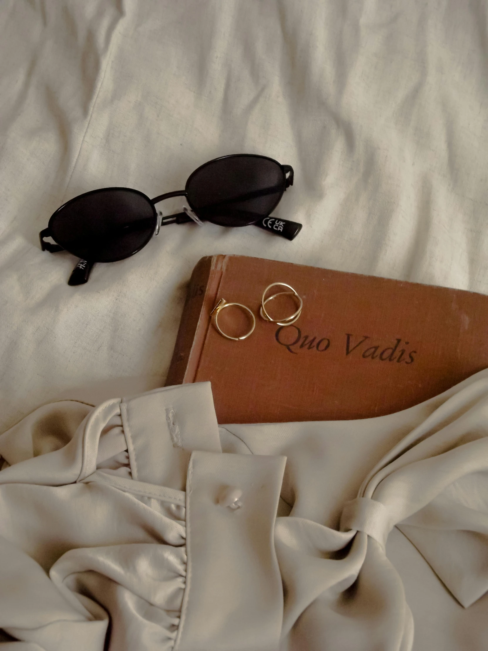 an open book and pair of sunglasses on a white sheet