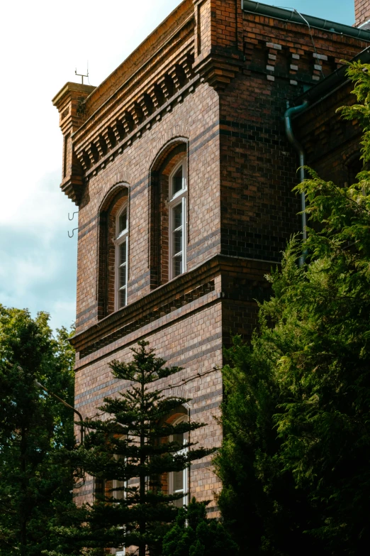 a clock tower on top of a tall brick building surrounded by trees