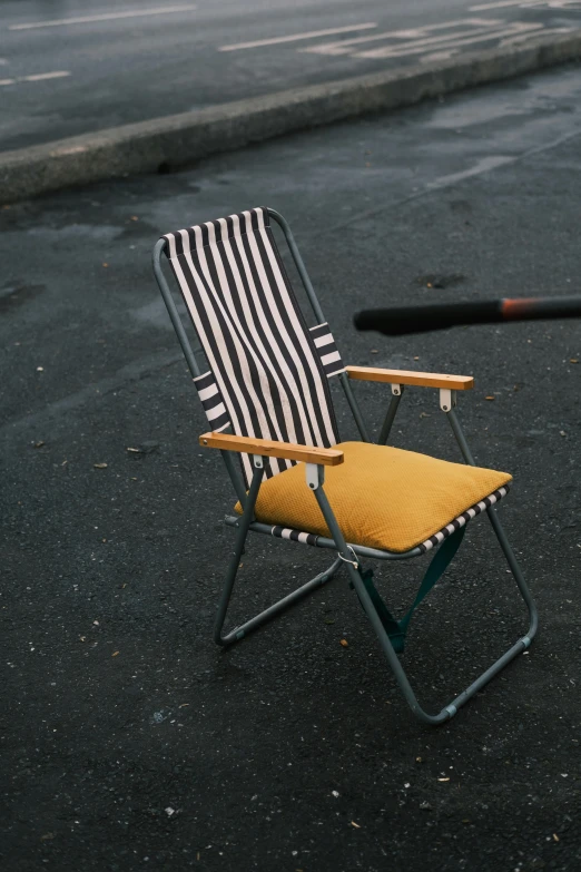 an empty chair sits on the street and has striped cover