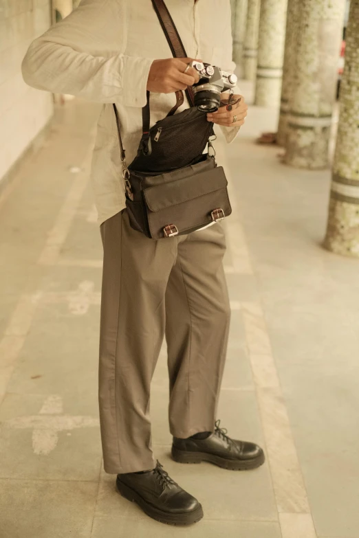 a man standing on sidewalk holding a camera bag