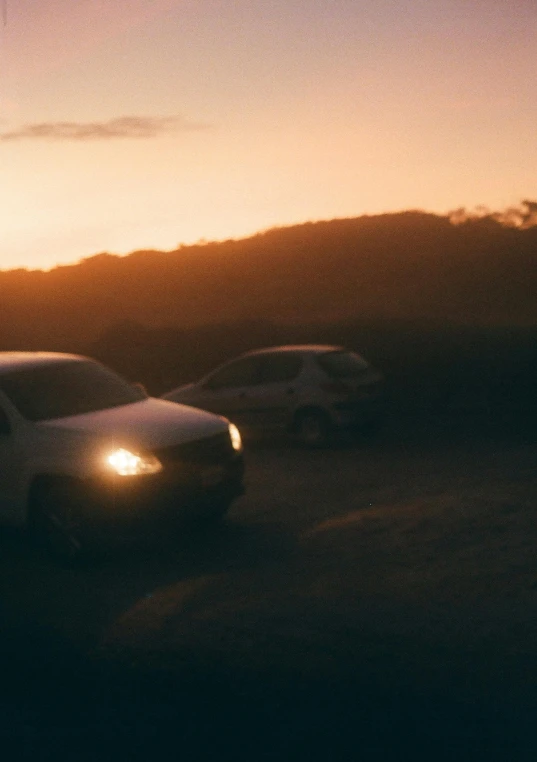 a picture of two cars driving on the road with the sun setting