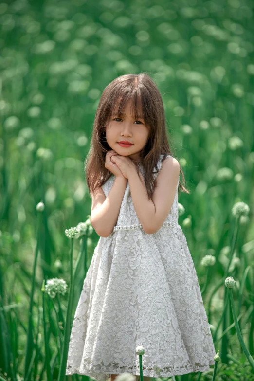 a girl in a white dress standing on top of a green field