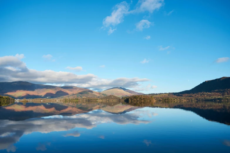 a small calm lake that has mountains in the background