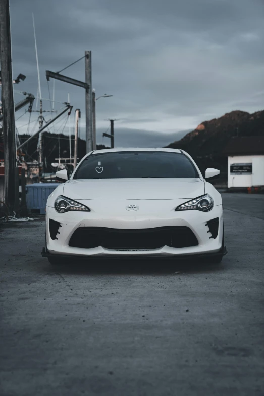 the white toyota car is parked next to a dock