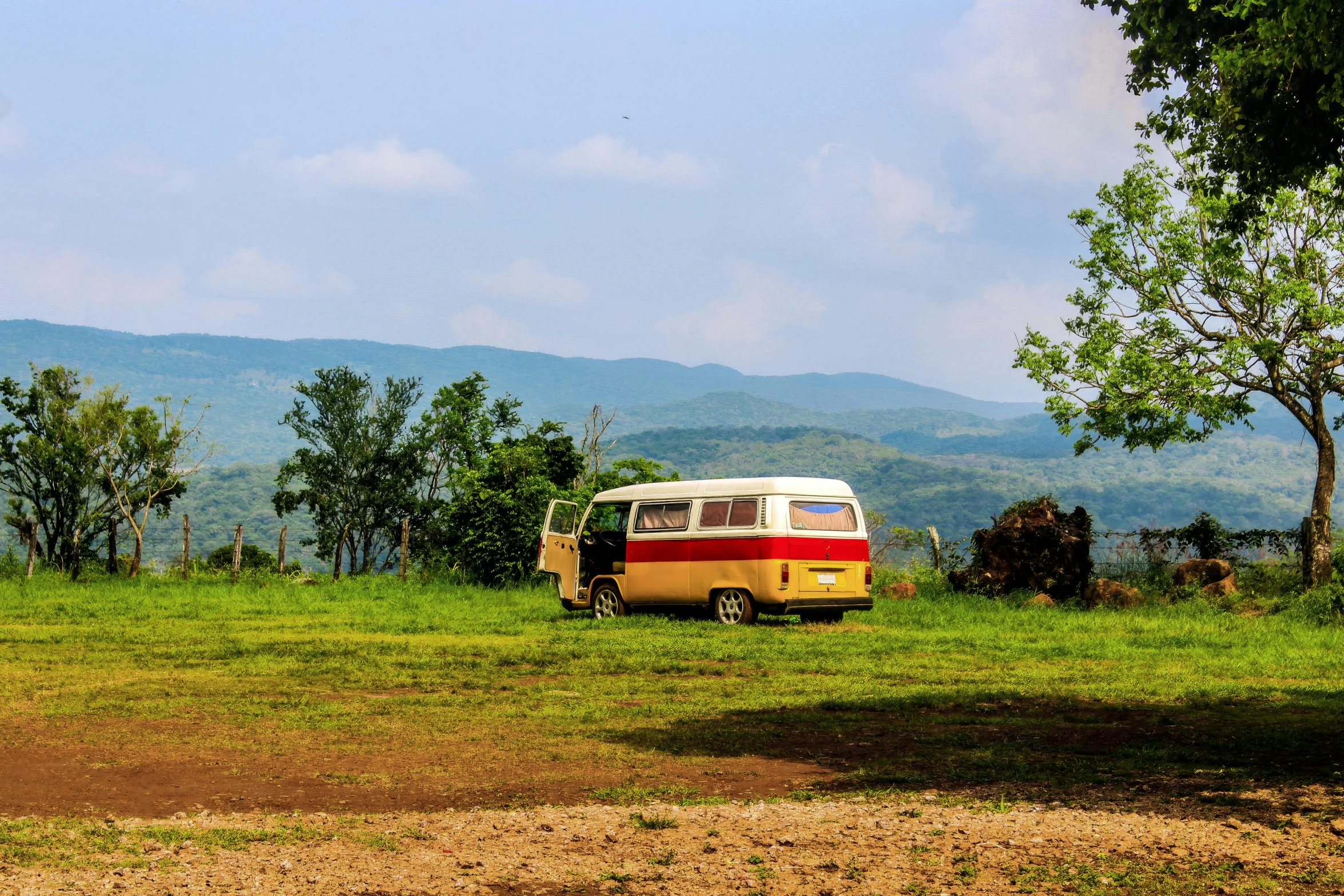 a small white and red bus on a grassy field