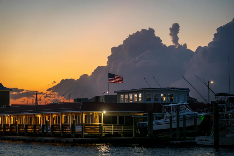 the sun is setting behind a boat docked in the water