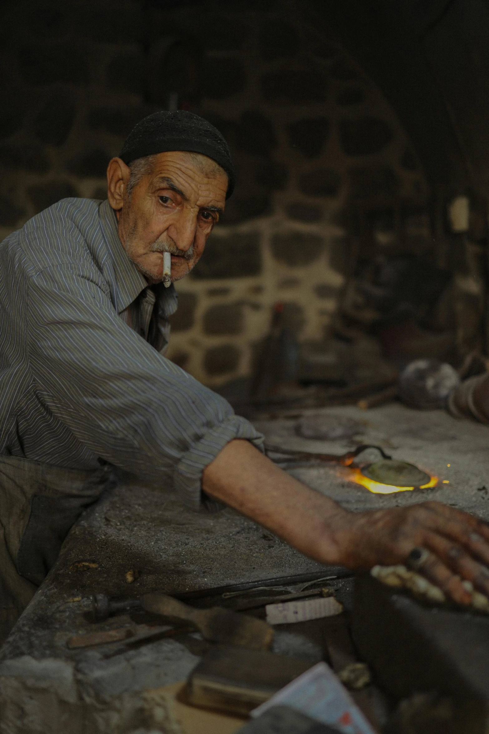 an older man smokes a cigarette in a hut