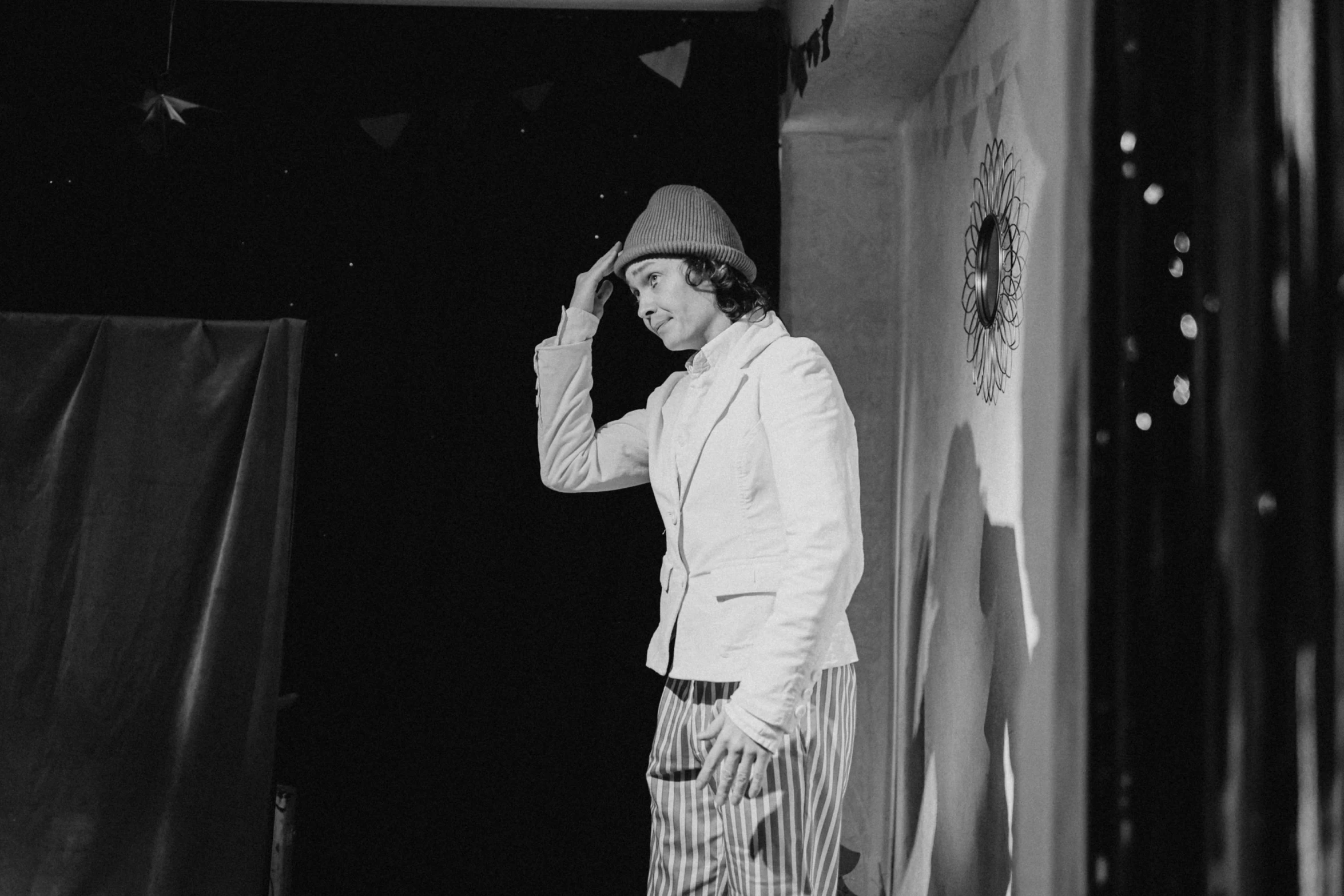 black and white pograph of a person in striped pants and jacket with a hat