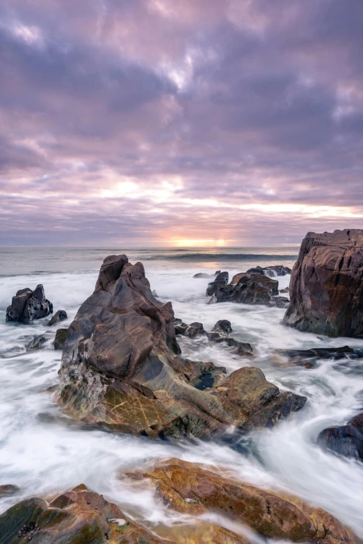 this is a po of a rock and ocean at sunset