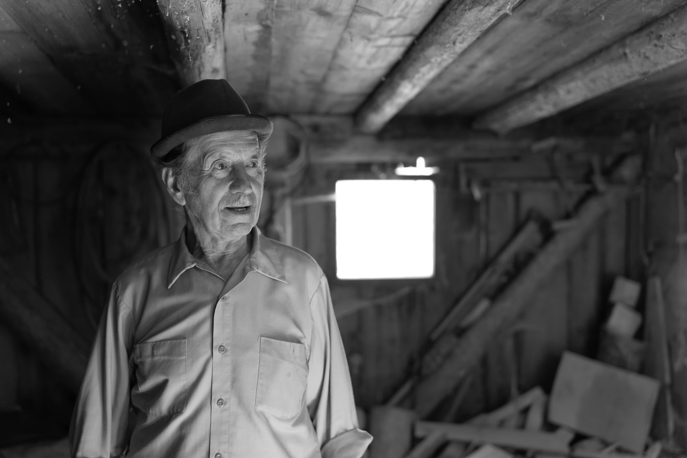 an old man in hat and plaid shirt standing in a doorway