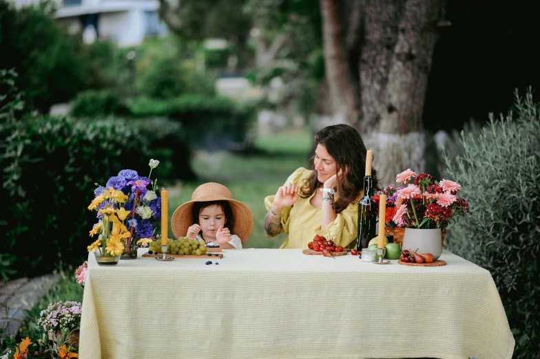 there is a lady holding a cup while sitting at a table