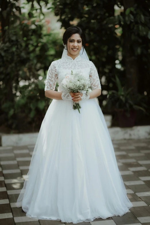 a young bride poses in her dress and bouquet