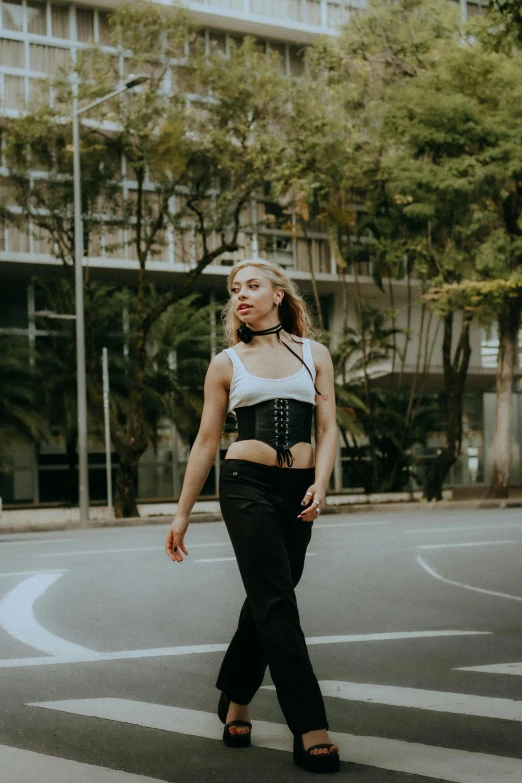 a beautiful young blond wearing black pants and laces while walking on the street