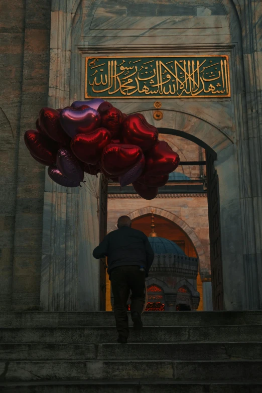 a man walking up the steps holding bunches of balloons