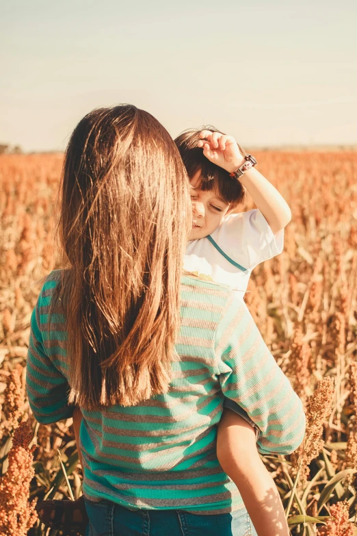 the back of a child holding their mother in the middle of the field