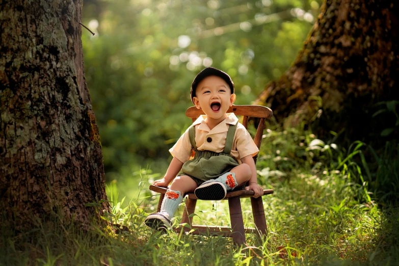 a toddler sits on a wooden chair next to a tree