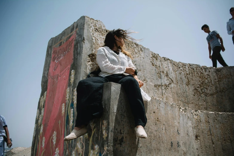 woman sitting on the wall, talking on her cell phone