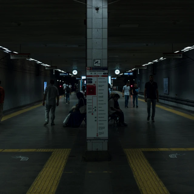 a subway station with a platform where people can be seen walking or sitting