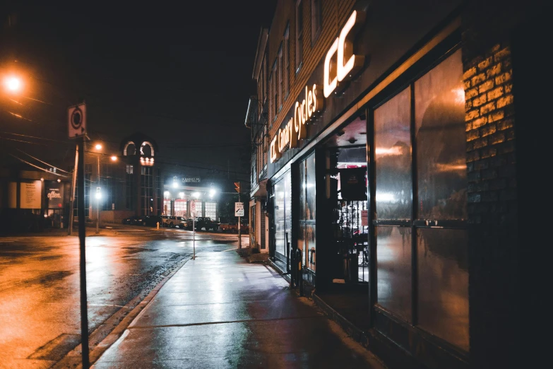 a store on a sidewalk is lit by streetlights