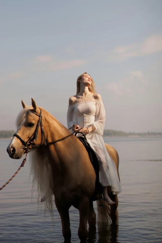 woman on a horse in the water with the ocean in the background