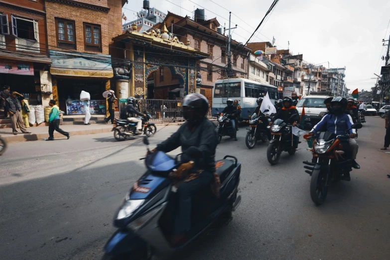 motorcycles riding down a street with a bunch of pedestrians
