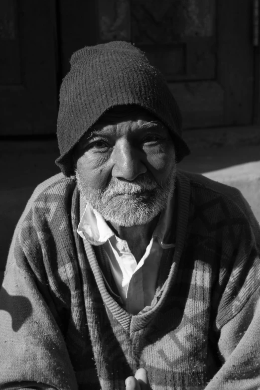 an old man wearing a hat sits on a couch