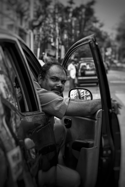 black and white pograph of man sitting in car