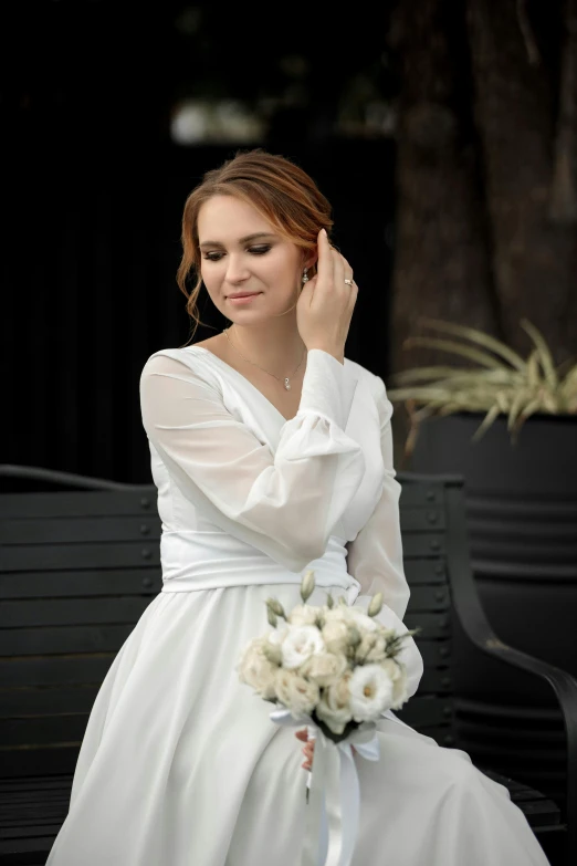 a woman wearing a white dress sitting on a bench