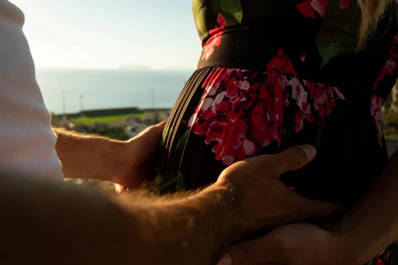 there is a woman in a floral dress hugging her belly