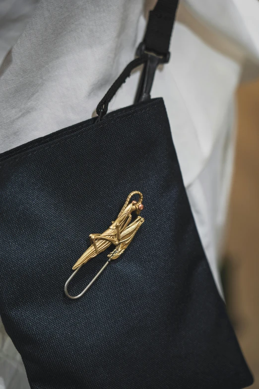 a black purse with gold hardware on a white shirt