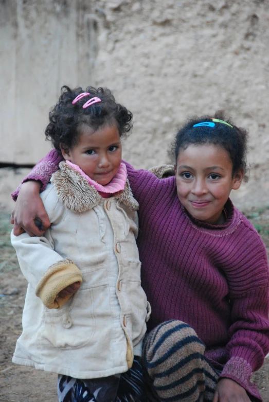 two girls sitting side by side in a desert setting