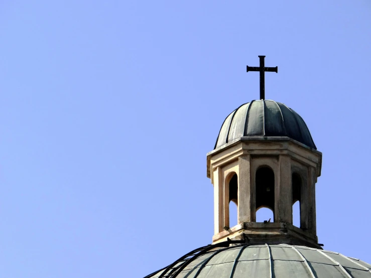 a cross sitting on top of a dome on top of a building