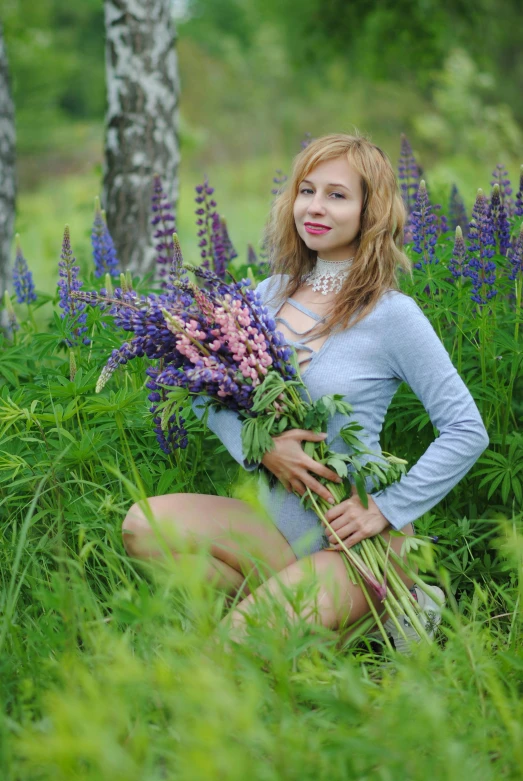 a woman with flowers is posing in the middle of tall grass