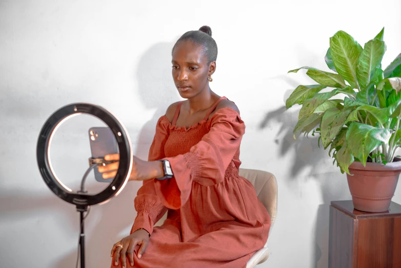 a woman wearing red dress sitting in chair looking at mirror